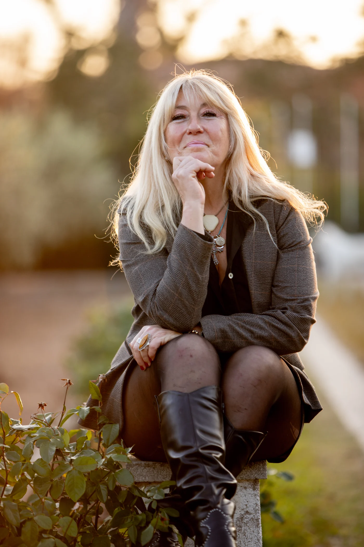 Rachel Paling seated in a sunlit garden, resting her chin on her hand